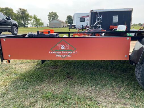 Skid-steer equipped with brush mower in overgrown field.